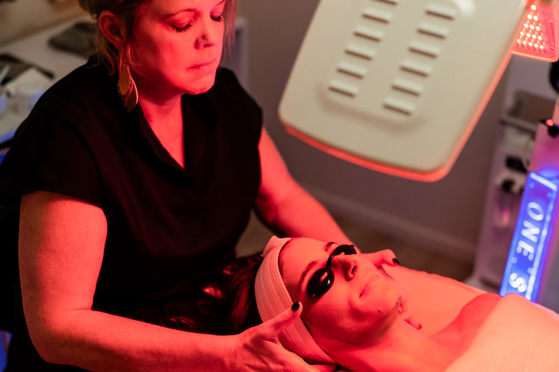 An esthetician massages a woman’s face in a facial spa in Flower Mound TX.