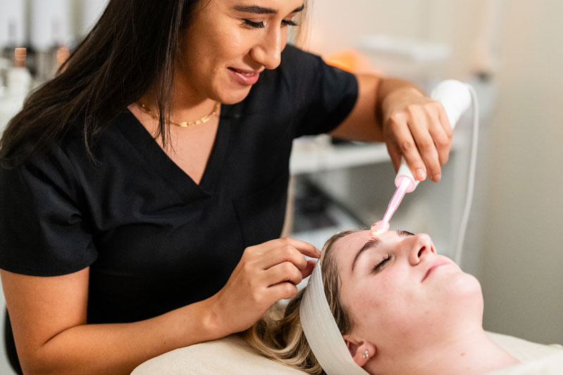 An esthetician massages a woman after a high frequency skincare treatment in Flower Mound, TX.